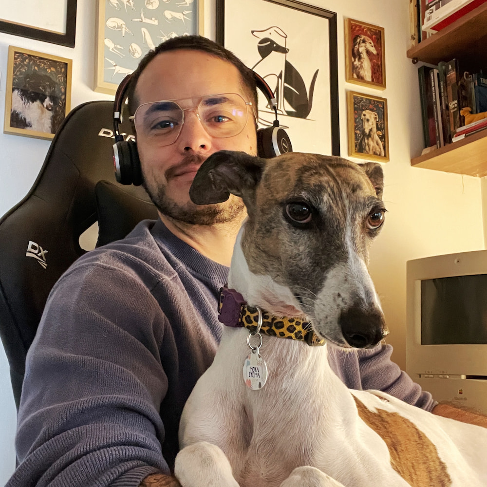 Imagen de Carlos trabajando en su escritorio y, sentado arriba de él, la galguita Mora Crema, una de sus amores.